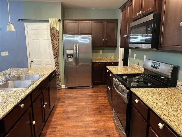 kitchen with dark hardwood / wood-style floors, stainless steel appliances, sink, dark brown cabinetry, and pendant lighting