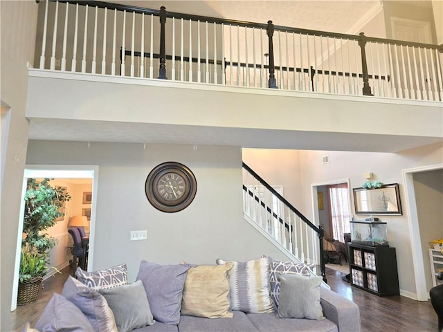 living area featuring stairs, a high ceiling, baseboards, and dark wood-style flooring