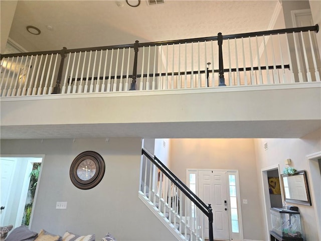 foyer entrance with visible vents, a high ceiling, and stairs