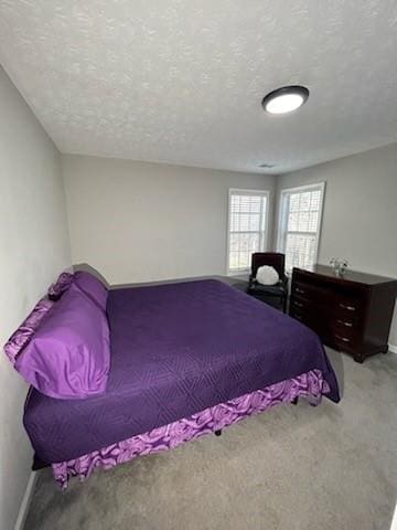 bedroom featuring light carpet, baseboards, and a textured ceiling