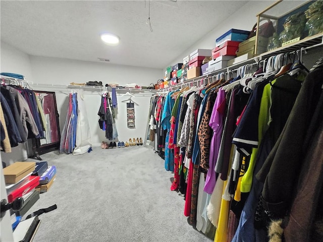 spacious closet with light carpet, visible vents, and attic access