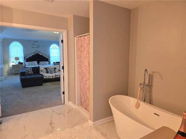 full bathroom with marble finish floor, a soaking tub, ensuite bath, and baseboards