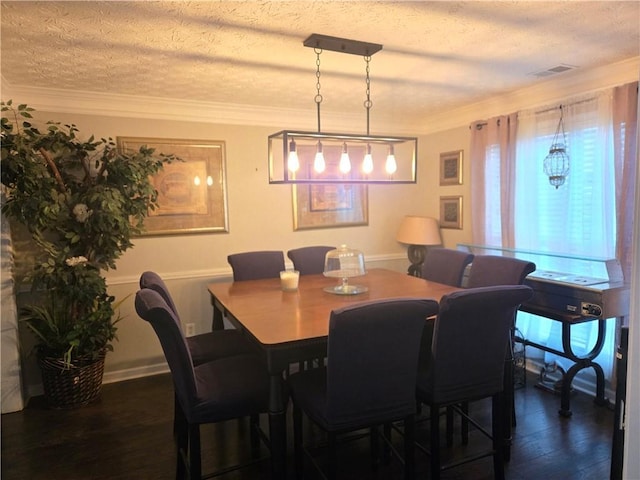 dining room with crown molding, a textured ceiling, visible vents, and dark wood-type flooring