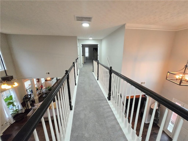 corridor featuring visible vents, a chandelier, carpet flooring, and an upstairs landing