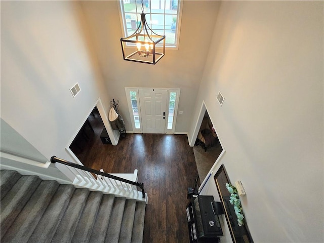 entryway with stairs, dark wood-type flooring, a towering ceiling, and visible vents