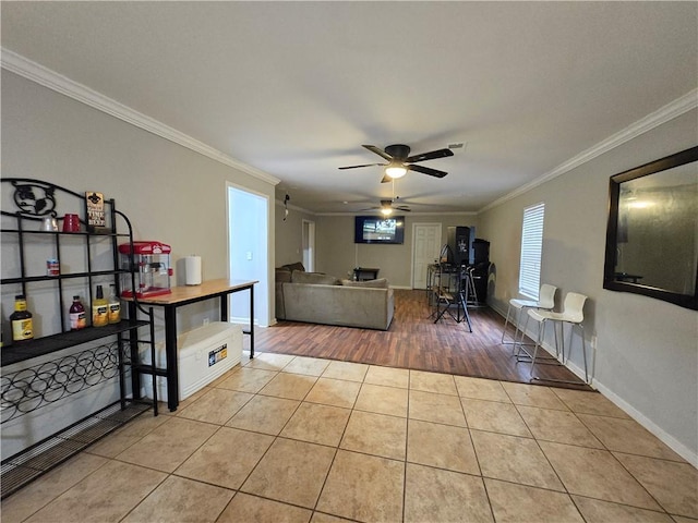 living area featuring light tile patterned flooring, crown molding, baseboards, and ceiling fan