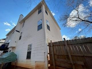 view of side of property with fence and a chimney