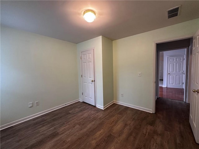 unfurnished bedroom with visible vents, baseboards, and dark wood-type flooring