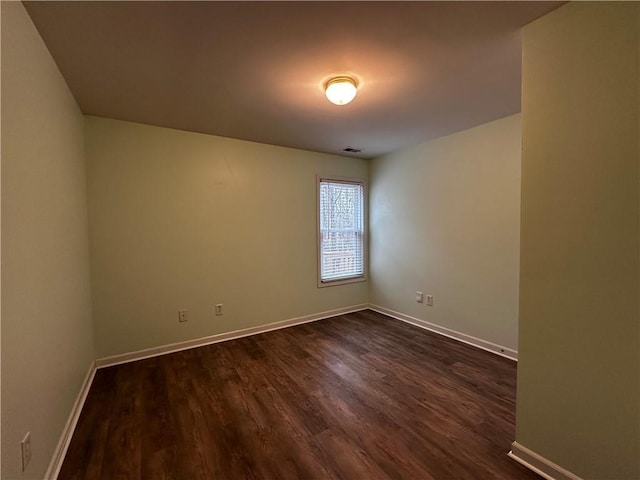 spare room with visible vents, baseboards, and dark wood finished floors