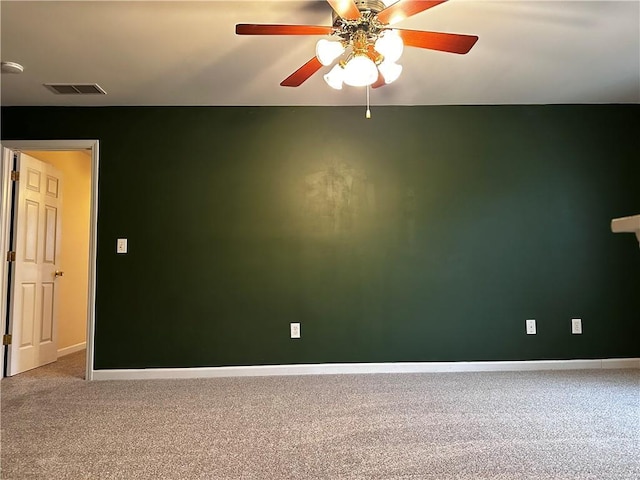 carpeted spare room with visible vents, a ceiling fan, and baseboards