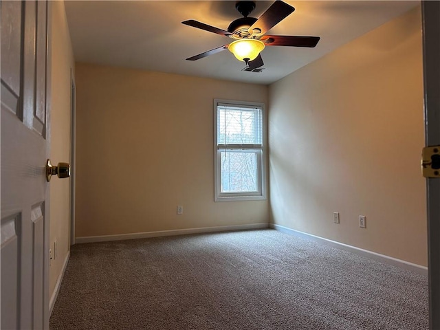 carpeted spare room with ceiling fan and baseboards