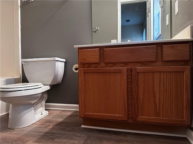 full bath with a tub, baseboards, toilet, wood finished floors, and vanity