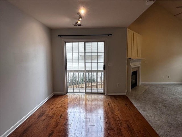 unfurnished living room featuring baseboards, a large fireplace, and wood finished floors