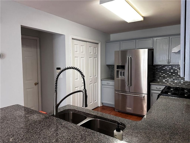 kitchen featuring gray cabinetry, a sink, tasteful backsplash, high quality fridge, and black range with gas stovetop