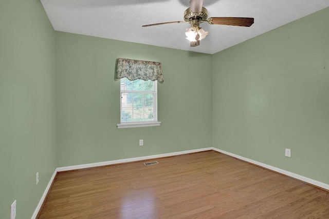 spare room with visible vents, baseboards, ceiling fan, and wood finished floors