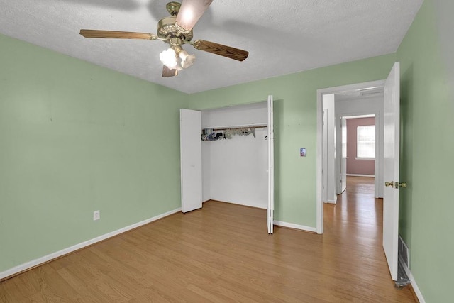 unfurnished bedroom with baseboards, a textured ceiling, wood finished floors, and a closet