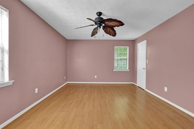 unfurnished room with light wood-style floors, baseboards, ceiling fan, and a textured ceiling