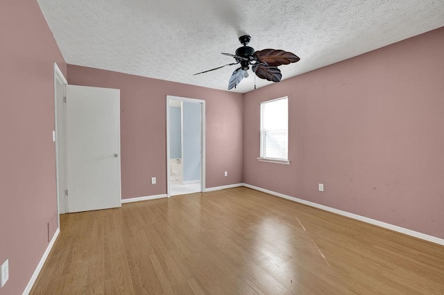 unfurnished room with baseboards, a ceiling fan, a textured ceiling, and wood finished floors