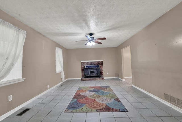 unfurnished living room featuring a textured ceiling, ceiling fan, visible vents, and light tile patterned floors