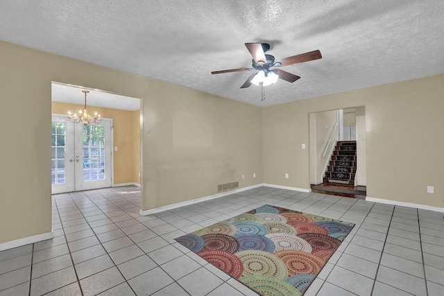 tiled empty room featuring a textured ceiling, visible vents, stairway, and ceiling fan with notable chandelier