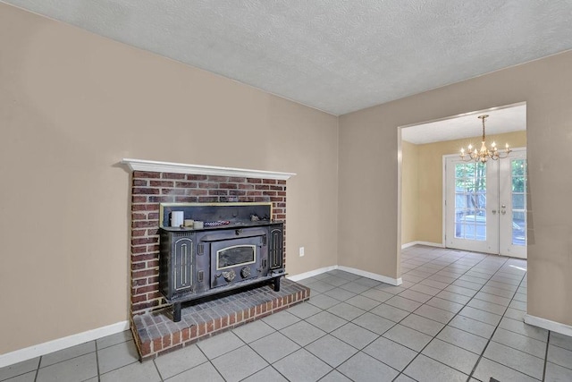 unfurnished living room with a textured ceiling, a wood stove, tile patterned floors, baseboards, and an inviting chandelier