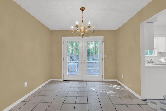 unfurnished dining area with light tile patterned flooring, baseboards, french doors, a sink, and a notable chandelier