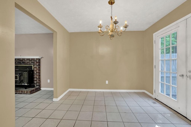 unfurnished dining area featuring an inviting chandelier, a textured ceiling, baseboards, and light tile patterned floors
