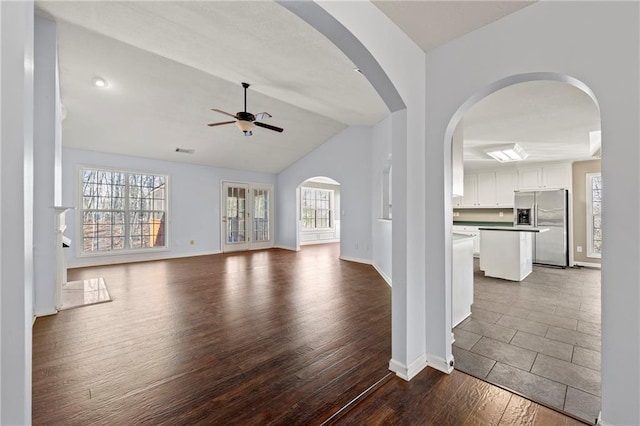 unfurnished living room featuring dark wood-type flooring, plenty of natural light, ceiling fan, and lofted ceiling