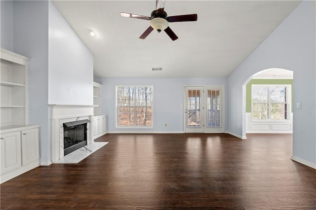 unfurnished living room featuring dark hardwood / wood-style flooring, ceiling fan, a healthy amount of sunlight, and a premium fireplace