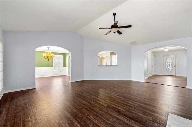 unfurnished living room with ceiling fan with notable chandelier, plenty of natural light, dark wood-type flooring, and vaulted ceiling