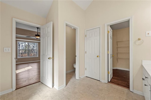 interior space featuring ceiling fan, vanity, lofted ceiling, and toilet