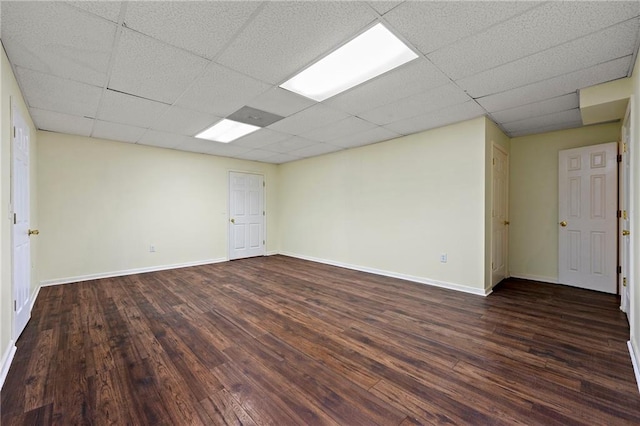 spare room with a paneled ceiling and dark hardwood / wood-style floors