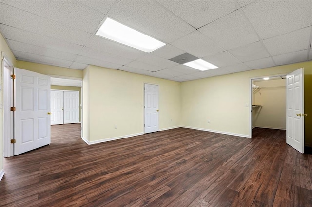 empty room with dark hardwood / wood-style flooring and a drop ceiling