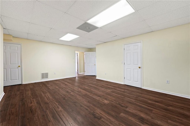 unfurnished room featuring dark hardwood / wood-style floors and a drop ceiling