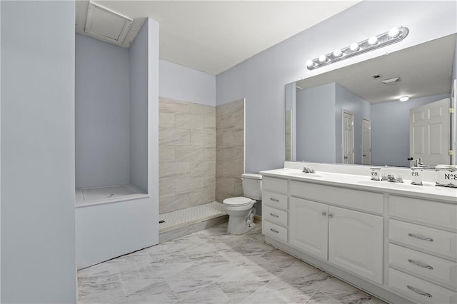 bathroom featuring a tile shower, vanity, and toilet