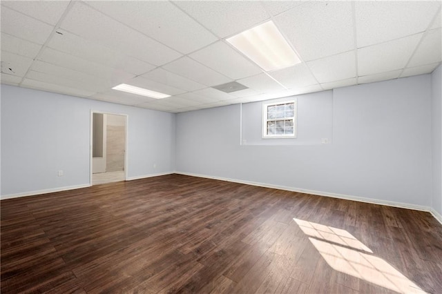 basement with a drop ceiling and dark hardwood / wood-style flooring