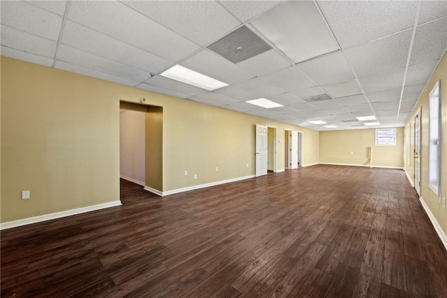 spare room with a drop ceiling and dark wood-type flooring