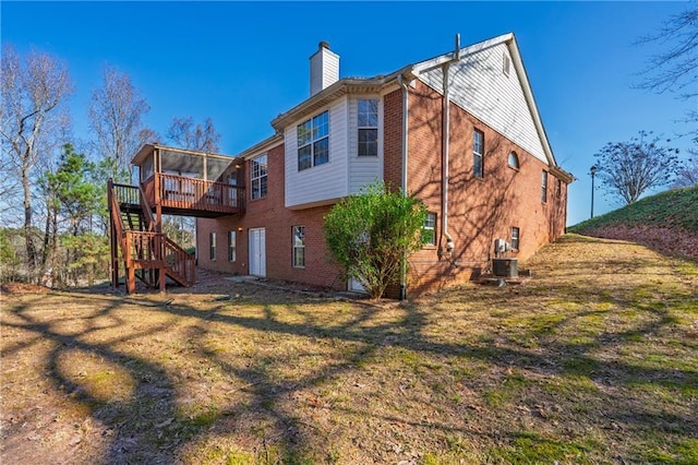 rear view of property featuring a lawn, central AC, a sunroom, and a deck