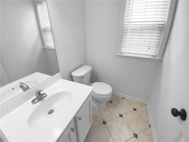 bathroom with tile patterned flooring, vanity, toilet, and a healthy amount of sunlight