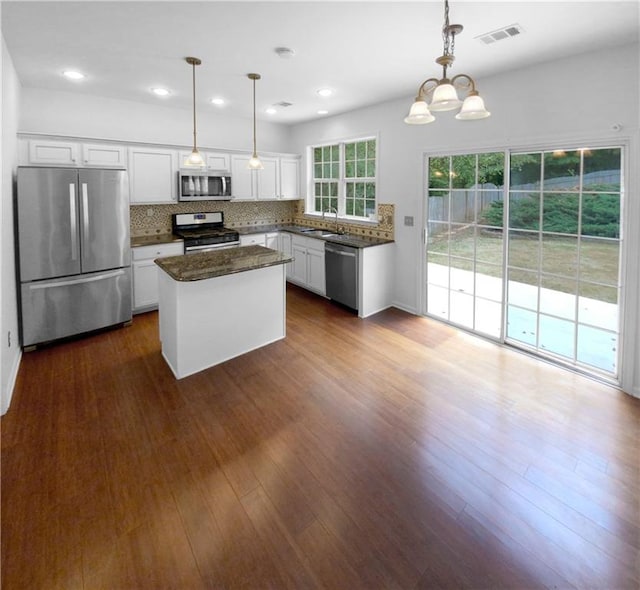 kitchen featuring a center island, pendant lighting, appliances with stainless steel finishes, and dark wood-type flooring