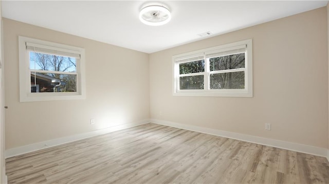 spare room featuring visible vents, light wood-type flooring, and baseboards