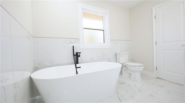 full bathroom with toilet, marble finish floor, and a freestanding bath