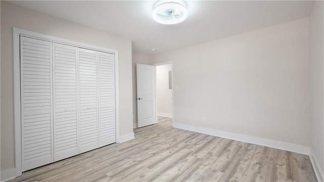 unfurnished bedroom with a closet, baseboards, and wood finished floors