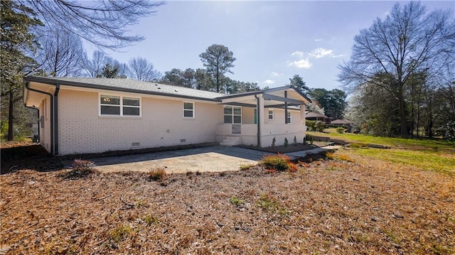 rear view of property featuring a patio, brick siding, and crawl space