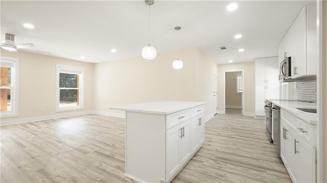 kitchen featuring recessed lighting, light countertops, light wood-style floors, appliances with stainless steel finishes, and pendant lighting