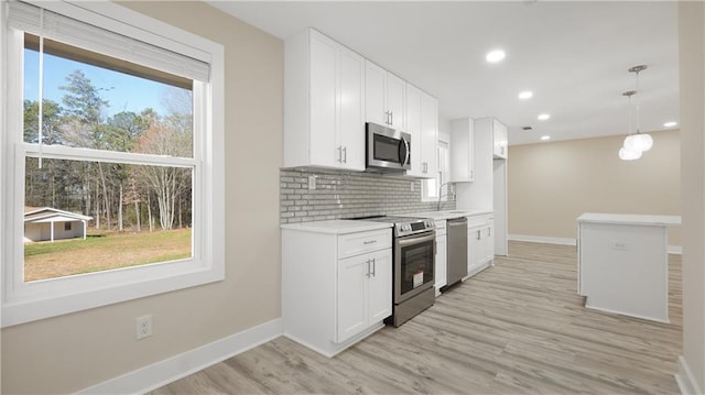 kitchen featuring baseboards, stainless steel appliances, decorative backsplash, white cabinets, and light wood-type flooring