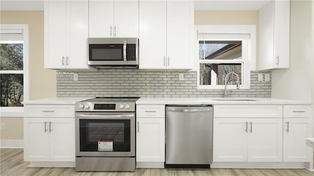 kitchen with a sink, plenty of natural light, appliances with stainless steel finishes, and white cabinetry