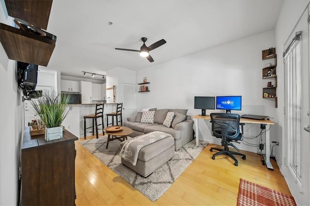 living area with rail lighting, wood-type flooring, and a ceiling fan