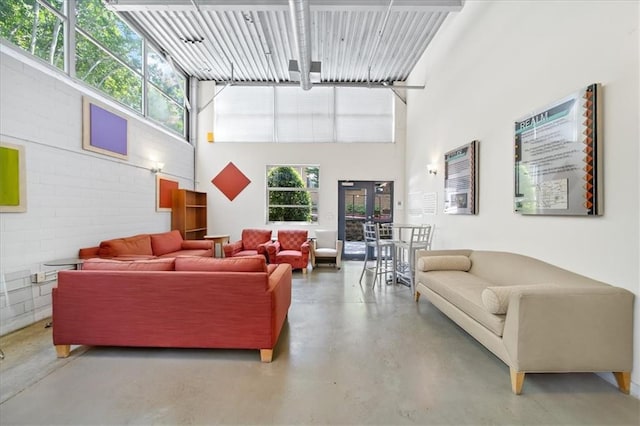 living area with concrete flooring, brick wall, and a high ceiling