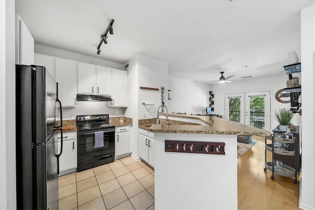 kitchen with under cabinet range hood, a peninsula, white cabinets, backsplash, and black appliances